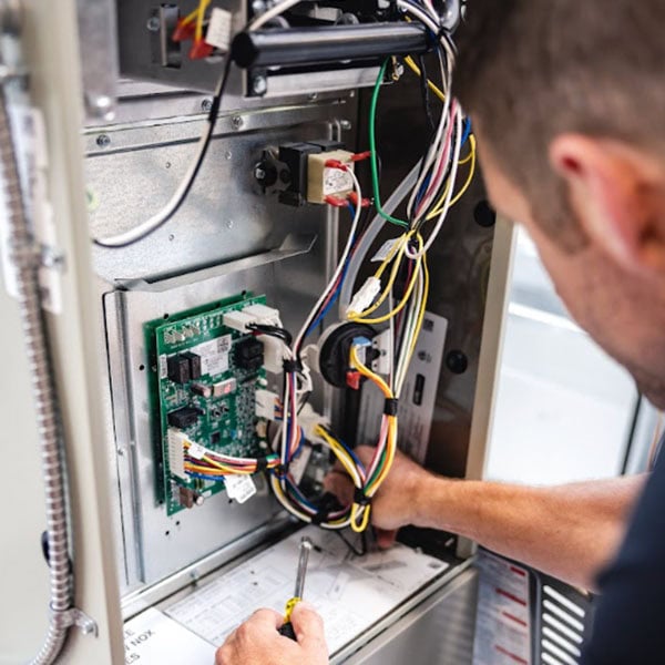 Schedule Your Annual Furnace Inspection Now. A technician inspecting a furnace.
